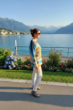 Model wearing the Isabella Palm Knit Top by Rosa Jojo, with a scenic lake backdrop and mountains in the distance.