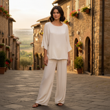 Eva Crew Neck top styled with relaxed pants in a scenic cobblestone street.