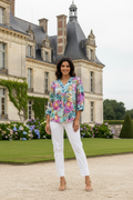 Model wearing Selaron Flared Sleeve Top with vibrant floral print in front of a grand chateau.