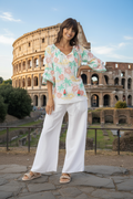 Escape Carol top worn by a model in front of the Colosseum, showcasing vibrant colors and tassel details.