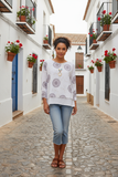 Model wearing the Majita Medallion Top with denim in a charming street setting, showcasing its floral pattern.