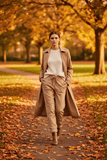 Model showcasing WL Shiny Crinkled Pant in a scenic autumn park with fallen leaves.