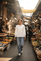 Model in WL Crossover Sweater walking through a vibrant market filled with fresh fruits and vegetables.