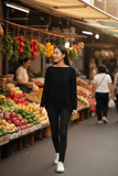 Model wearing WL Crossover Sweater while strolling through a vibrant market filled with fresh produce.