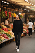 Model wearing WL Crossover Sweater while strolling through a vibrant market filled with fresh produce.