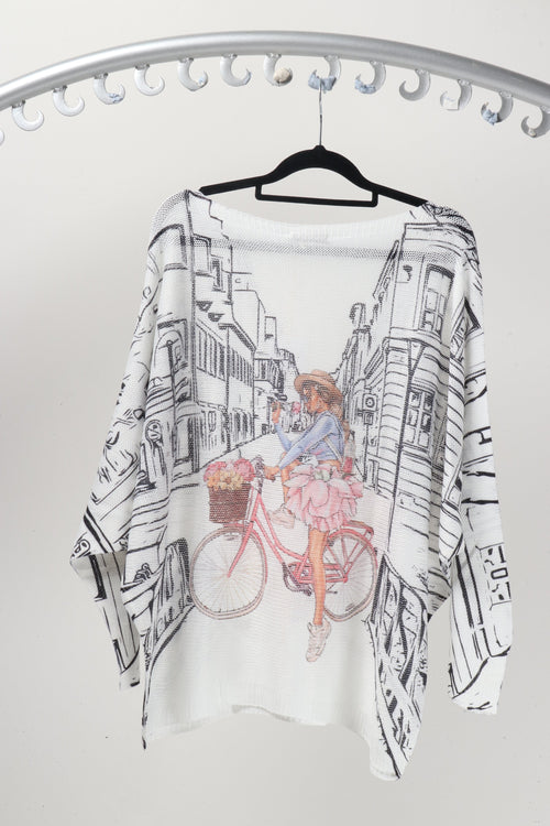 Bike Rider in Paris Knit featuring a whimsical design of a girl cycling in a charming street scene.
