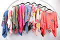 WL Floral Linen top collection on hangers showcasing floral patterns in various colors and styles.