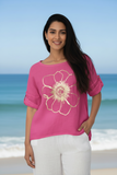 Model wearing the Golden Flower Linen Top with a gold flower design against a beach backdrop.