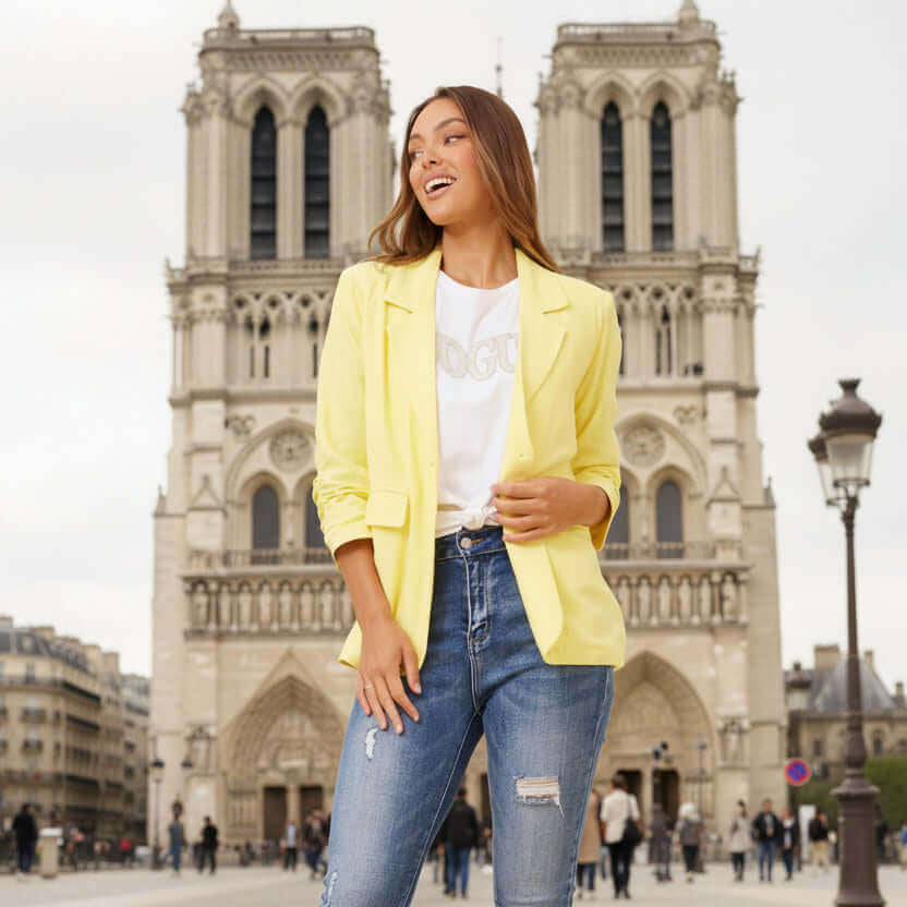Model wearing Limoncello Linen Blazer in lemon yellow with chic jeans, set against a stunning urban backdrop.