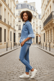 Stylish woman wearing Marni Denim Jacket with frill trim, standing on a cobblestone street, showcasing casual elegance.