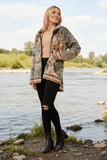 A woman wearing the stylish Perfect Hood Jacket by Bottega Moda by a river, showcasing its floral design and relaxed fit.