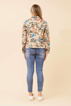 Back view of a woman wearing the CKM Tapestry Jacket with floral patterns, paired with blue jeans and white shoes.