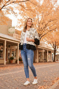 Woman wearing a stylish Jaipur Shirt with jeans, standing on a charming street lined with autumn trees.