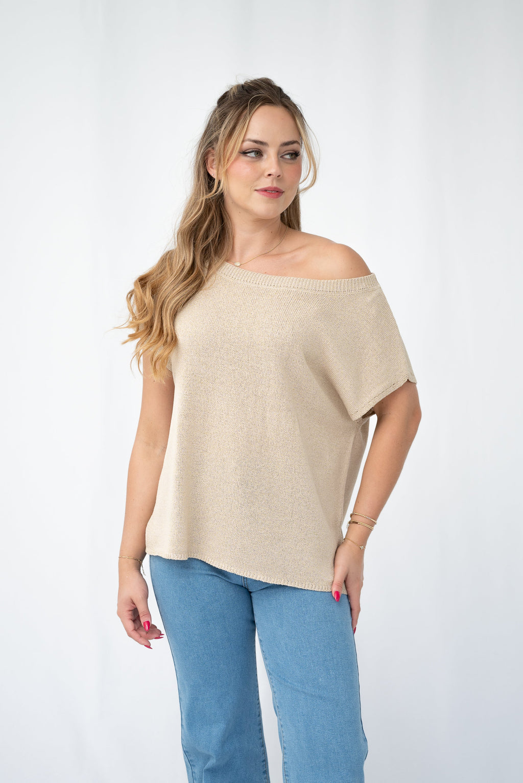Model wearing a Crepe yarn knit top with an off-shoulder style and casual jeans.