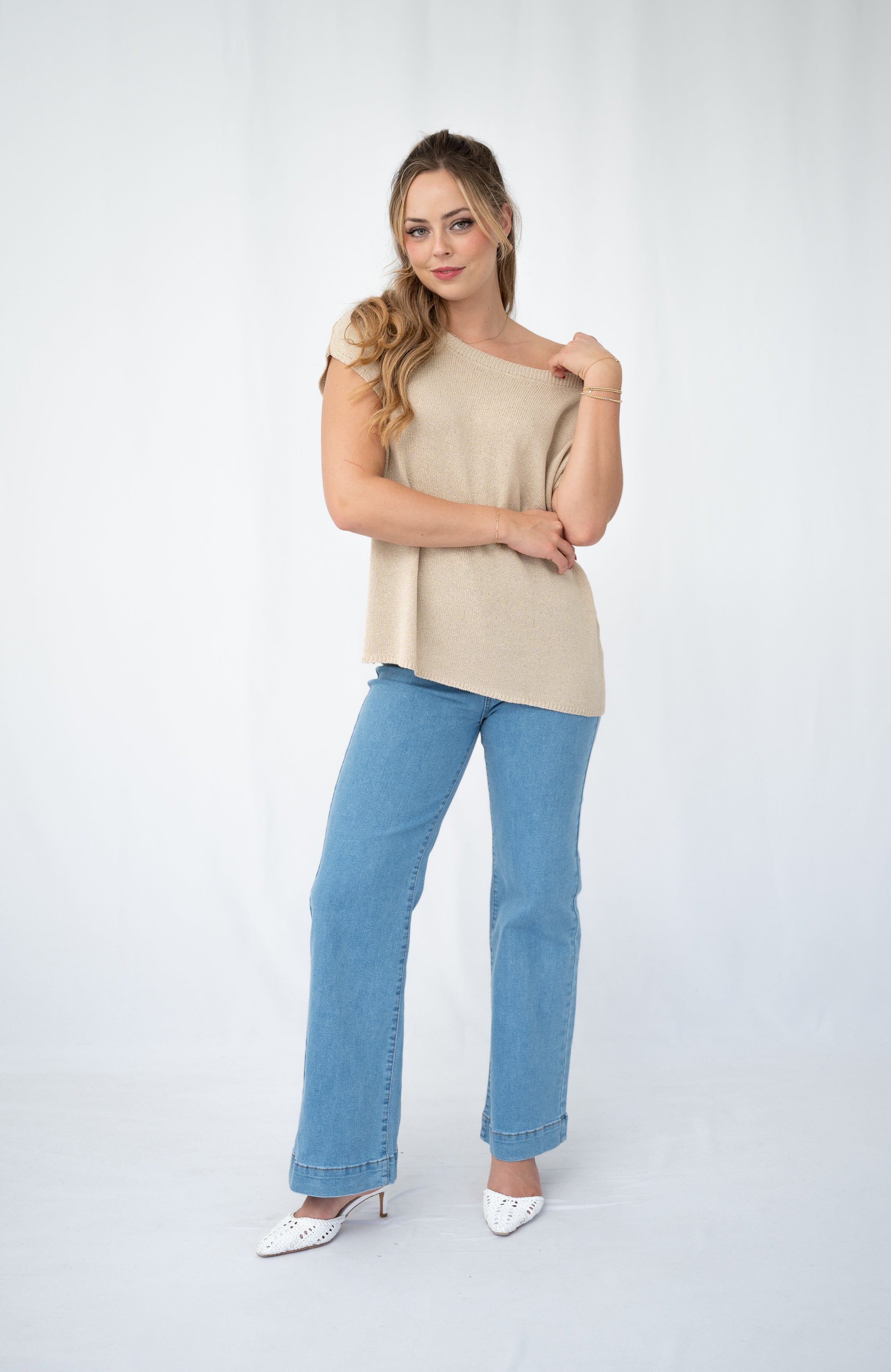 Woman wearing a stylish Crepe yarn knit top with a scoop neckline and relaxed fit, paired with blue jeans.