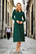 Model wearing the Ckm Zoe Dress, a green midi dress with a high neck and zip closure, strolling in a city street.