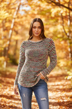 Model showcasing the Sunniva Multi Knit jumper in a scenic autumn setting with colorful foliage.