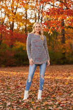 Model wearing the Sunniva Multi Knit jumper in a colorful fall scene with autumn leaves.
