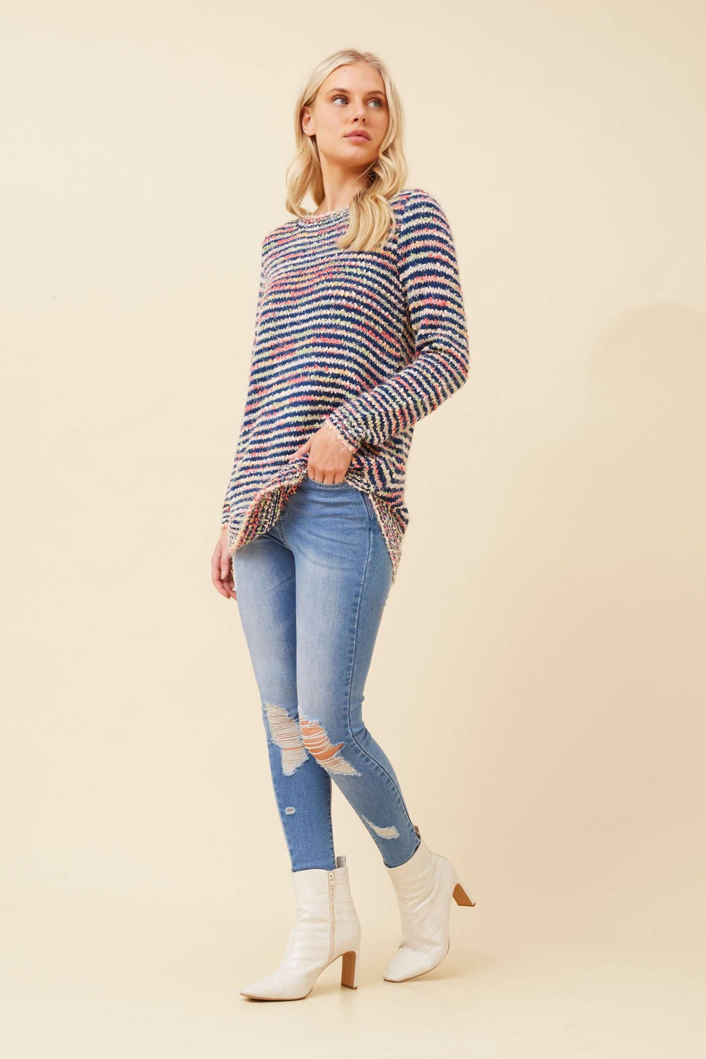Stylish model wearing the Sunniva Multi Knit jumper, paired with ripped jeans and ankle boots for a chic look.