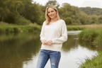 Model wearing the Erica Applique Knit in soft oatmeal by a serene waterway, showcasing floral appliqué details.
