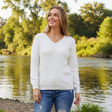 Model wearing the Rochelle Pearly Jumper by a river, showcasing its elegant pearl button detailing in a natural setting.