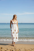 Model wearing a Tropicanna Sundress on the beach, featuring vibrant florals and pineapples.