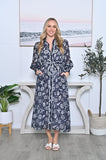 Model wearing Starfish Dress, a maxi-length dress with long sleeves, tie belt, and pockets, featuring a navy base with white print.
