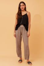 Model showcasing Roma Linen Pants with a stylish black tank top against a warm background.