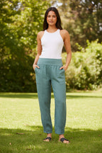 Model wearing Roma Linen Pants in a garden setting, showcasing comfort and style with an elastic waistband.