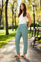 Model wearing Roma Linen Pants in green, showcasing Italian elegance and comfort in a sunny park.
