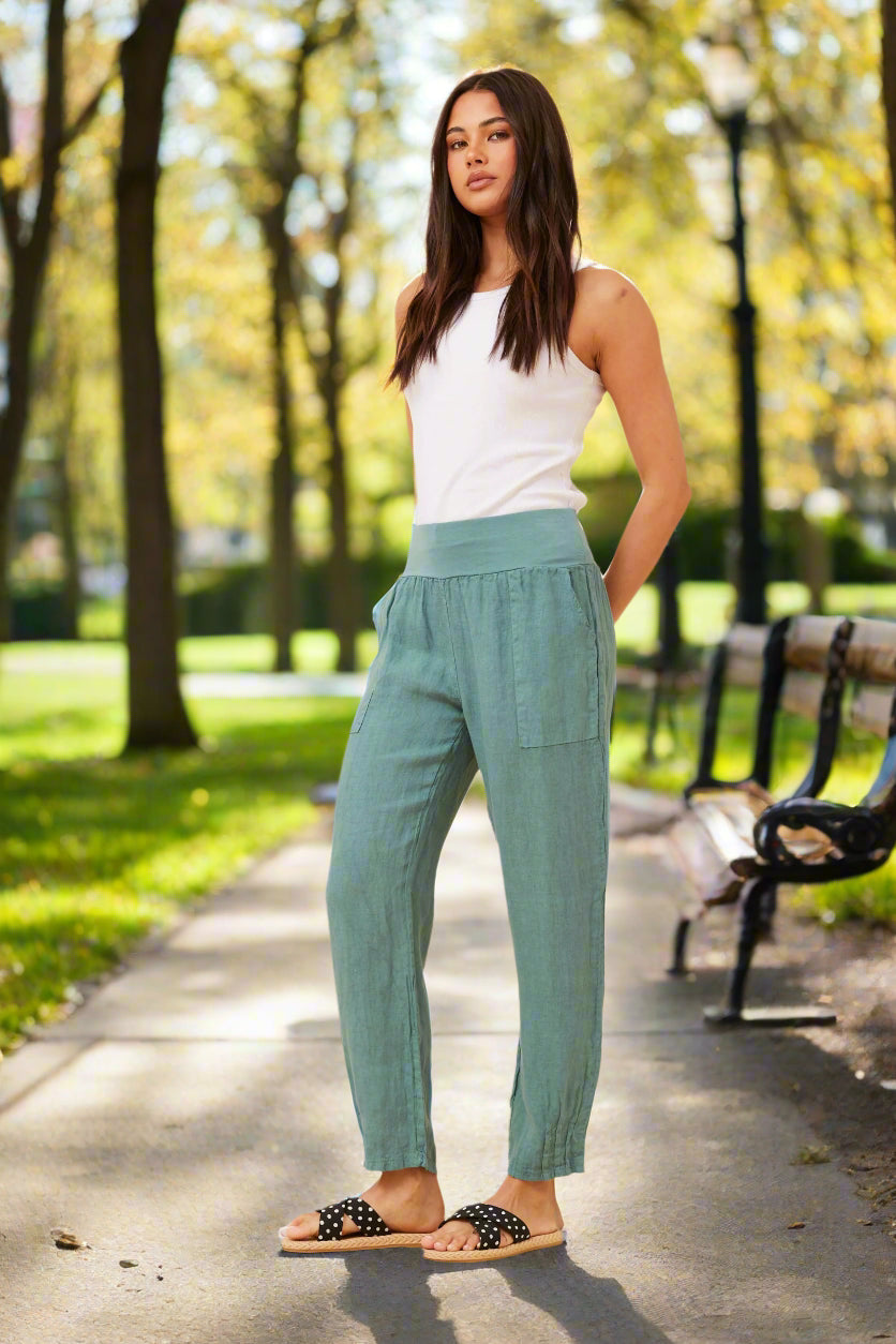 Model wearing Roma Linen Pants in green, showcasing Italian elegance and comfort in a sunny park.
