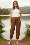 Model wearing Roma Linen Pants by Bottega Moda, standing by the water in nature.