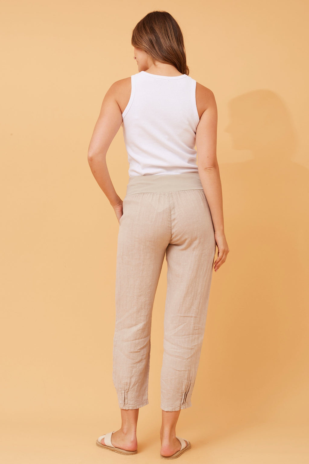 Back view of a model wearing Roma Linen Pants by Bottega Moda, showcasing comfortable elastic waist and elegant structure.
