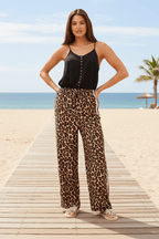 Wildcat Racer Pants showcased on a model at the beach, featuring a relaxed fit and leopard print design.