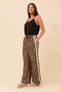 Woman wearing Wildcat Racer Pants with leopard print and double stripe detail, showcasing sporty sophistication and comfort.