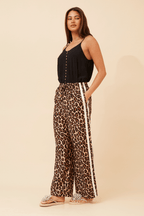 Woman wearing Wildcat Racer Pants with leopard print and double stripe detail, showcasing sporty sophistication and comfort.