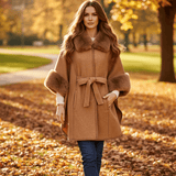Woman in a park wearing the Anya Cape with faux fur trim, showcasing its stylish design and cozy fit.