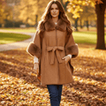 Woman in a park wearing the Anya Cape with faux fur trim, showcasing its stylish design and cozy fit.