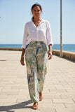 Model walking by the beach in Peacock in Palace Pants and a white shirt, showcasing stylish comfort.