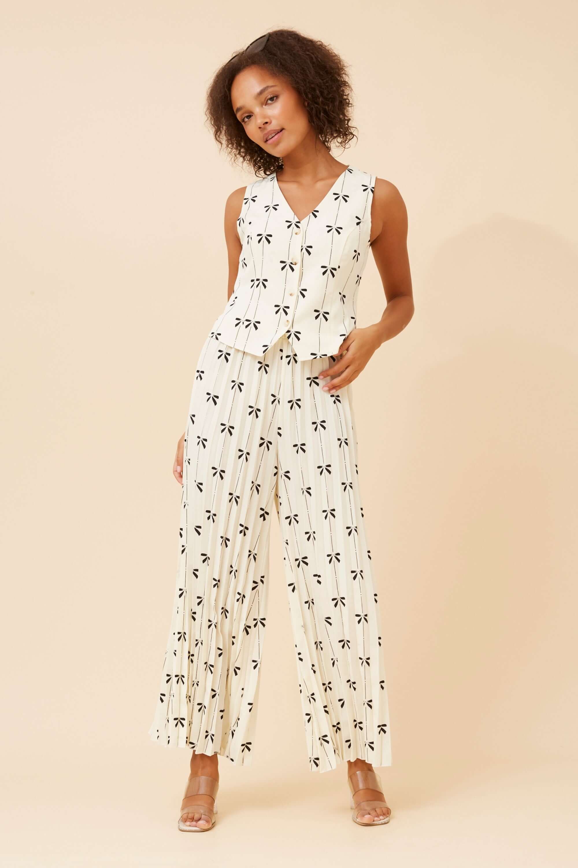 Model wearing Maja Bows Pant Set featuring a sleeveless top and wide leg pleated pants with black bow print.