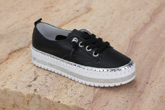Susan Sneakers -black with dazzling diamante sole and eyelets on a stone background.