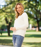 Model wearing a lightweight Pearl Knit top with elegant pearl embellishments in a sunny park setting.