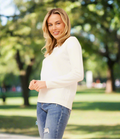 Model wearing a lightweight Pearl Knit top with elegant pearl embellishments in a sunny park setting.