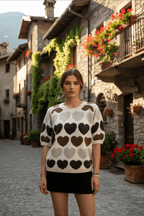 Maja Multi Short sleeve Jumper displayed in a charming village setting, showcasing its heart pattern and relaxed style.