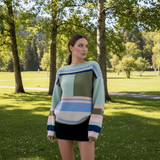 Model wearing Maja Multi Jumper against a snowy mountain backdrop, showcasing its vibrant colors and relaxed fit.