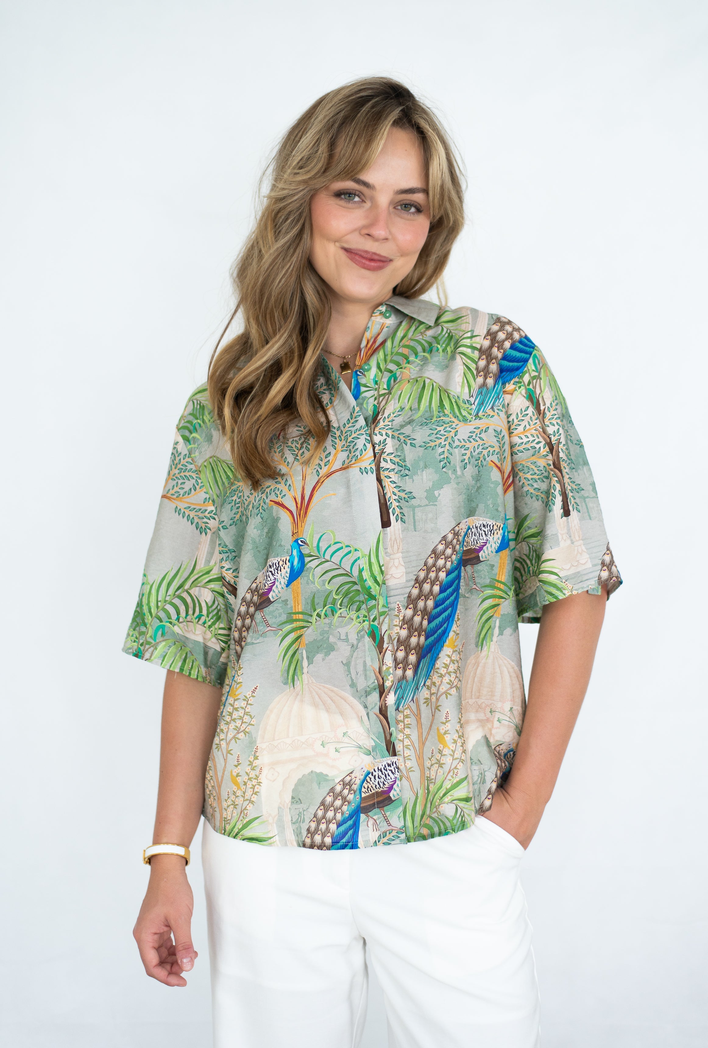 Model wearing Peacock in Palace shirt featuring vibrant peacock print and short sleeves, perfect for exotic elegance.