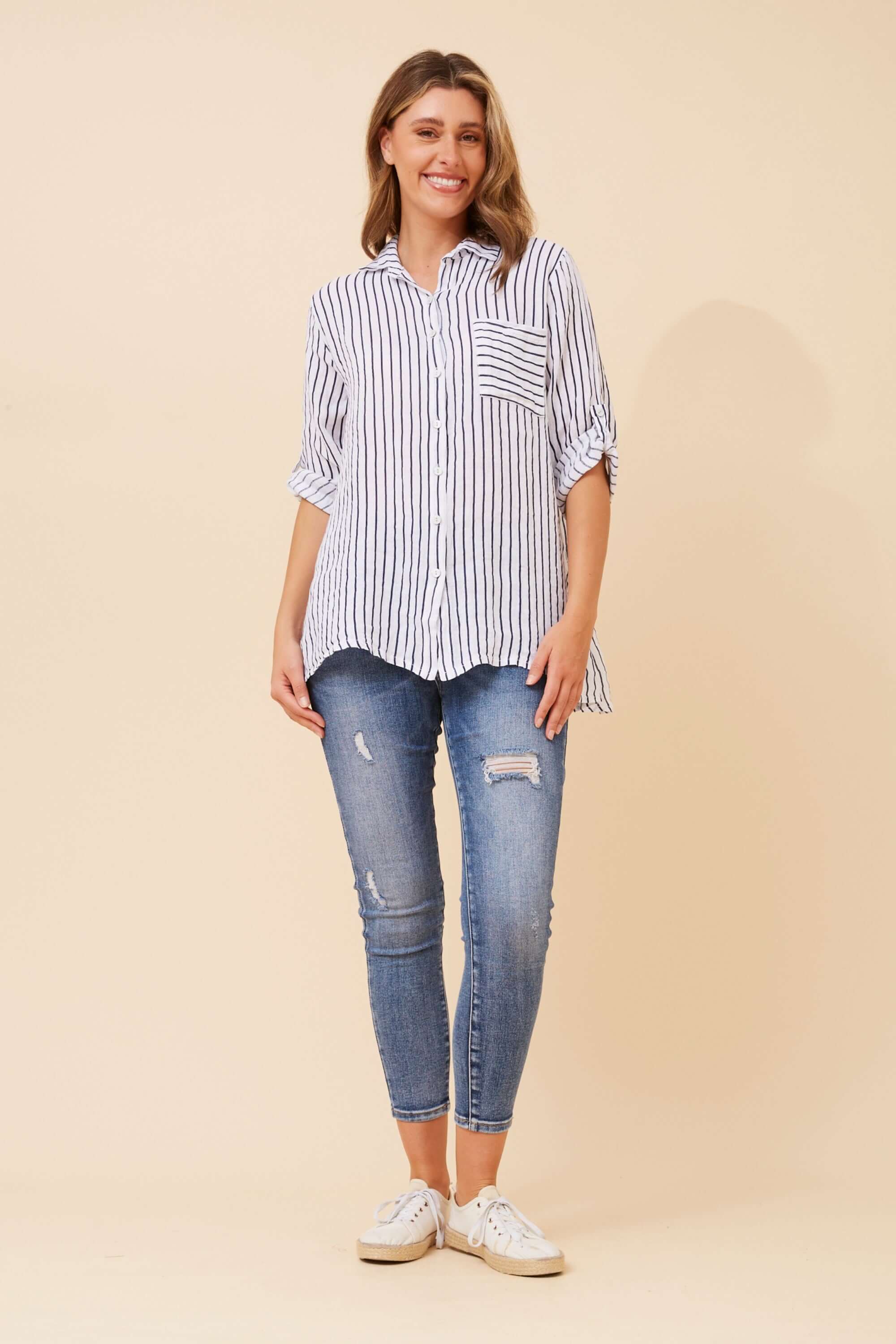 Model wearing the Alma Striped Shirt by Bottega Moda, featuring navy and white stripes and 3/4 roll-up sleeves.