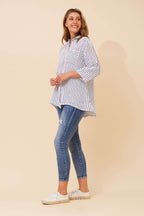 Model wearing Alma Striped Shirt by Bottega Moda with navy and white stripes and hi-lo hem.