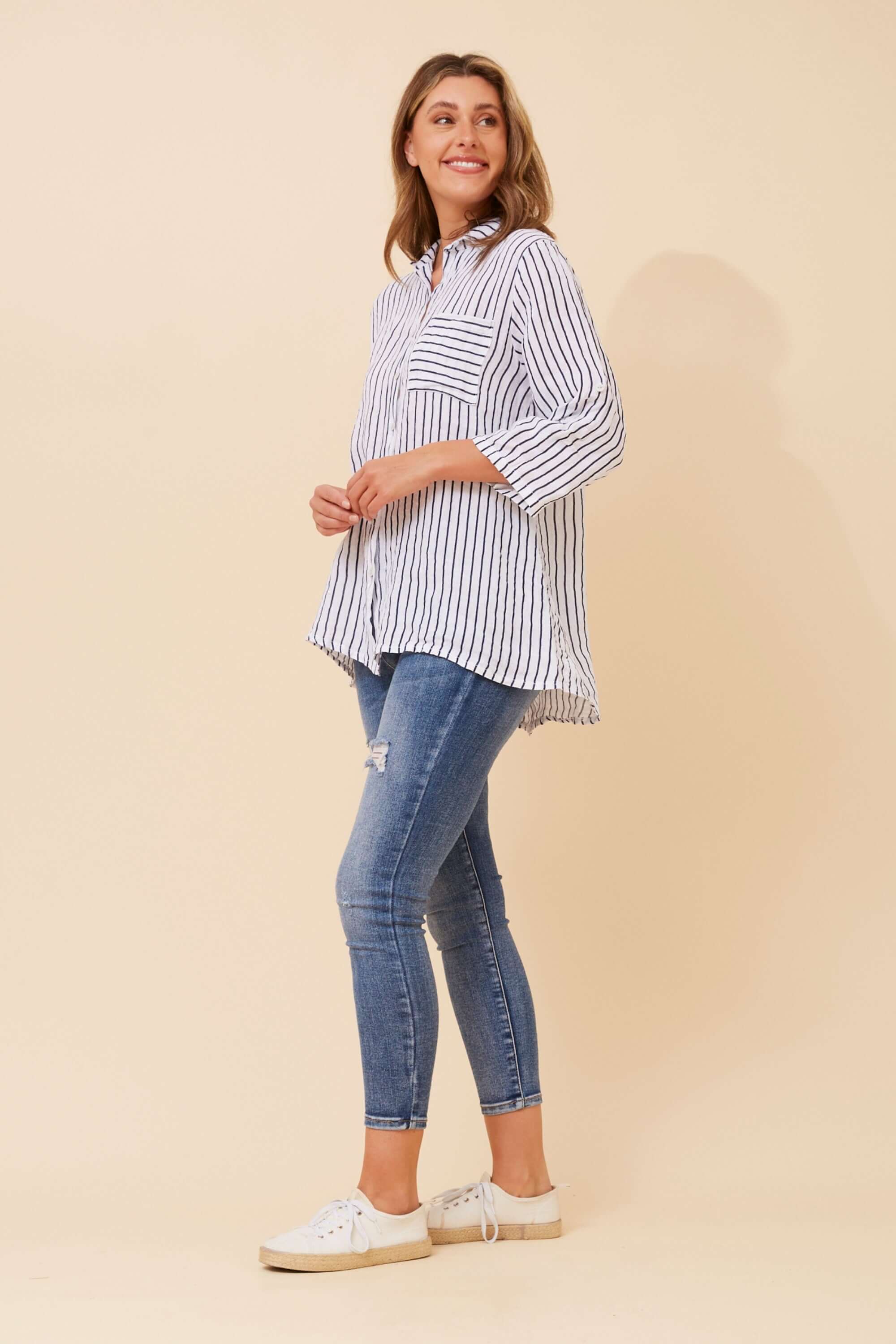 Model wearing Alma Striped Shirt by Bottega Moda with navy and white stripes and hi-lo hem.