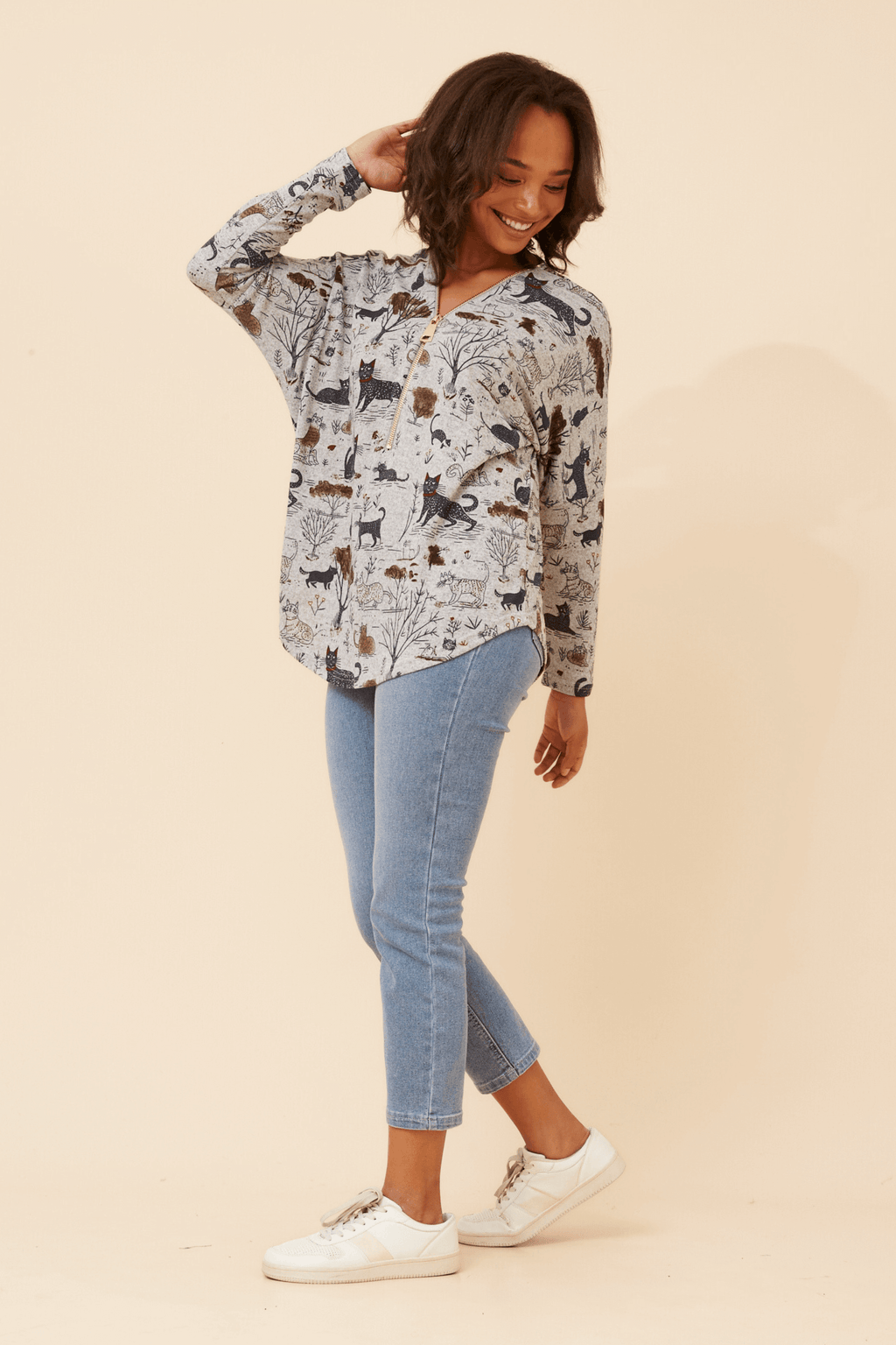 Model wearing the Leonor Cat Zip Top with playful cat print and relaxed fit, paired with stylish jeans.
